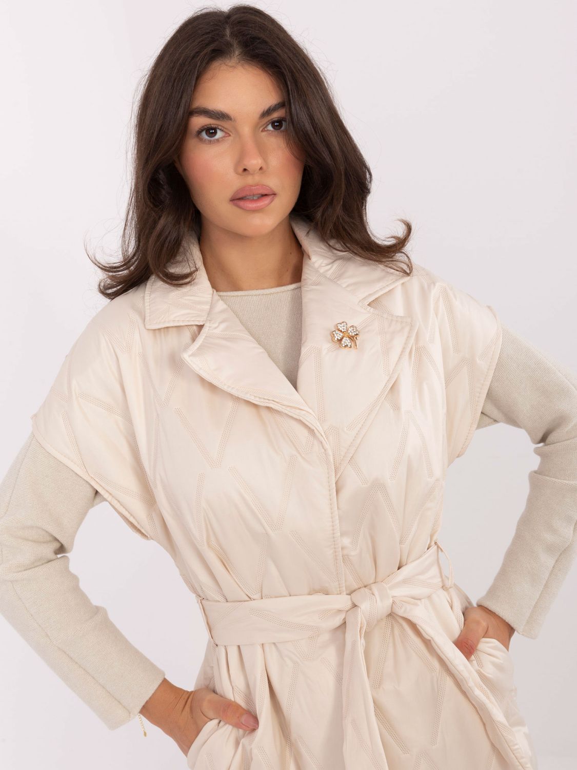 Elegante beige Steppweste mit Gürtel und Brosche
